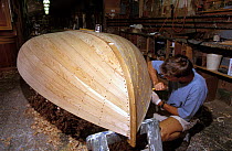 A traditional Beetlecat builder working on the bottom of a new boat at the International Yacht Restoration School in Newport, Rhode Island, USA.