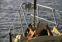 Man reading a book on the bow of a boat