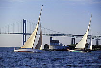 Two classic 12 metre yachts racing upwind in front of the Rose Island Lighthouse and the Newport Bridge, Newport, Rhode Island, USA.