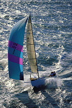 A J90 speeding downwind and surfing the waves with an asymmetric spinnaker off Newport, Rhode Island, USA.