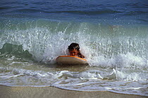 Young boy bodyboarding in the shallow breakers, Hawaii, USA.