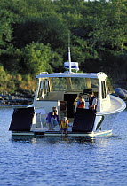 Family cruising aboard a Pearson 38 True North motorboat, with the transom doors open. Anchored in Narragansett Bay, Rhode Island, New England, USA. Model released.