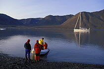 Crew of 88ft sloop "Shaman" make their way back to the yacht in an inflatable tender at a light 2 o'clock in the morning. Summertime on Spitsbergen, Svalbard, Norway, 1998.