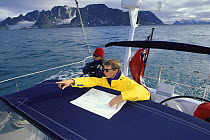 Crew aboard 88ft sloop "Shaman" navigating with map and pointing. Spitsbergen, Svalbard, Norway, 1998.