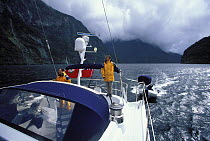 Crew aboard 88ft yacht "Shaman" motoring through fjords of South Island, New Zealand.