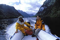 The crew of yacht 'Shaman' explore the Fjordland area by inflatable boat. South Island, New Zealand. Model Released.