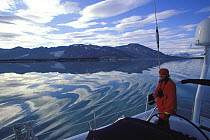 Ripples on smooth water as 88ft sloop "Shaman" motors around the coast of Spitsbergen, Svalbard, Norway 1998.