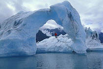 Man exploring a natural arch in weathered icebergs off a glacier in Alaska. 2001
