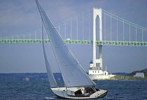 The small Starbuck cruises under the Newport Bridge, Rhode Island, USA with the Rose Island lighthouse in the background.