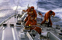 Crew in wet-weather gear working aboard yacht "Flyer", Whitbread Round the World Race 1981-82.