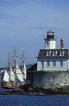 Tall ship 'Bounty' sailing behind the Rose Island Lighthouse off Newport, Rhode Island, USA.