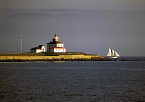 Schooner sailing past Watch Hill Lighthouse, on Watch Hill Point south of Westerly, at the entrance to Fisher's Island Sound, Rhode Island, USA.