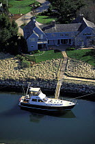 Aerial view of an elegant Cape Cod home with private mooring and a motorboat, Massachusetts, USA.