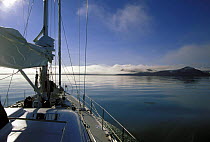 The 88 foot sloop, "Shaman", motoring through the mirror calm Arctic water in Spitsbergen, Svalbard, Norway, 1998. Property Released.