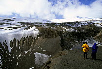 Hikers viewing the dramatic snow covered cliff faces of Deception Island, Antarctic Peninsula.