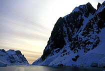 Still evening waters with snow covered mountains in the Lemaire channel, Antarctica.