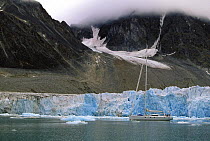 The 88 foot sloop "Shaman" motoring along the end wall of a glacier in Spitsbergen, Svalbard, Norway, 1998.