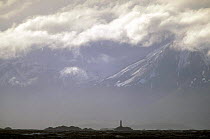 A marker in the Beagle channel with snow covered mountain behind, Tierra del Fuego, South America.