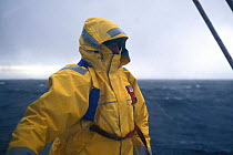 A crew member wearing offshore foul weather gear and a safety harness.