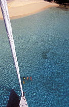 Aerial view from the masthead of the 88 foot sloop "Shaman", swimmers can be seen below in the clear waters of the Vava'u Group, Tonga, South Pacific. Model and Property Released.