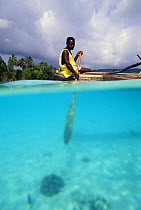 Split-level view of a man paddling his outrigger through the clear waters of Espiritu Santo Island, Vanuatu, South Pacific.