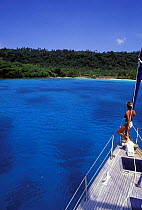 Woman looking to land from the bow of a yacht, Vanuatu, Pacific Islands. Model and Property Released.