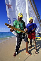 Two men rigging their dinghy on the beach at the Grenada Sailing Festival, Caribbean