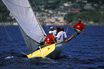 Crew member trapezing aboard a traditional workboat during a race at Grenada Sailing Festival, Caribbean.