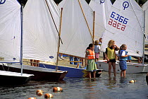 Children on the waterside at an Optimist sailing camp, Cape Cod, USA.