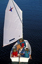 Mother and children sailing a Vanguard Pram dinghy. Model released.
