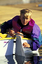 Young boy mounting the rudder in an Optimist dinghy during training in Florida, USA