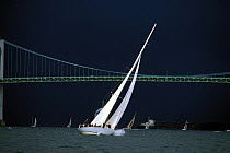 Storm clouds over the 12 Metre yacht ^Columbia^ as she sails under the Newport Bridge during the Museum of Yachting Regatta, Rhode Island, USA