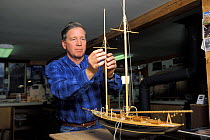 Model boat builder, Robert Eddy, working on the mast of a scale model of the 1915 Herreshoff schooner "Mariette" in his shop in Camden, Maine, USA.