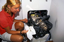 A crew member checking the engine oil level aboard a cruising yacht.