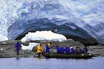 Cruise ship passengers in a zodiac exploring a natural ice cave, Antarctic Peninsula.