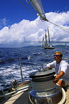Crew member trimming the jib on a superyacht racing in the St.Barths Bucket, Caribbean.
