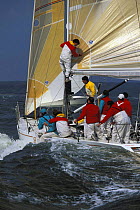 Crew member on the boom aboard a 50 foot Springbok while racing off Newport, Rhode Island, USA.