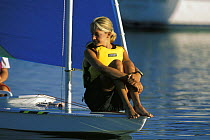 Girl balancing on the bow of a Sunfish dinghy, sailing in the early morning calm off Cape Cod, USA