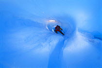Person climbing inside a cave carved by a river flowing inside the Perito Moreno glacier during summer, Patagonia, Argentina.