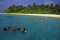 Divers on the surface with snorkellers in the background, Maldives.