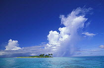 Small uninhabited coral island with dramatic clouds, Maldives, Indian Ocean.