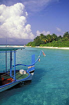 Dhoni, a traditional Maldivian boat, in front of an island, Maldives.