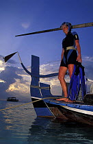 Woman with snorkeling gear standing on stern of a dhoni, the typical Maldivian boat, Maldives. Model released.