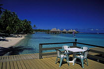Deck of bungalow with traditional Tahitian styled bungalows on stilts in the background, Kia Ora resort, Rangiroa, Polynesia.
