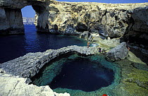 Scuba divers preparing to enter the giant azure pool at the Azure Window, a rock formation on the cliff-lined coast of Gozo, Malta