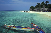Two boats moored in front of a beach with cottages on, Sipadan, Borneo