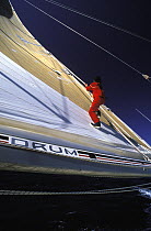 Crewman uses the reefing lines to climb the mainsail aboard "Drum" during the Whitbread Round the World Race, 1985.