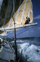 Crewman stands on the boom of "The Card" as the boat races through the Southern Ocean during the Whitbread Round the World Race, 1989-90.