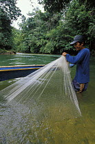 Iban man from the Nanga Sumpa longhouse collecting a castnet in front of a longboat on Delok river, Batang Ai, Sarawak, Borneo. 2002