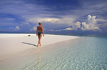 Woman walking on white sand surrounded by clear waters, Lankayan Island, Sabah, Borneo. Model released.